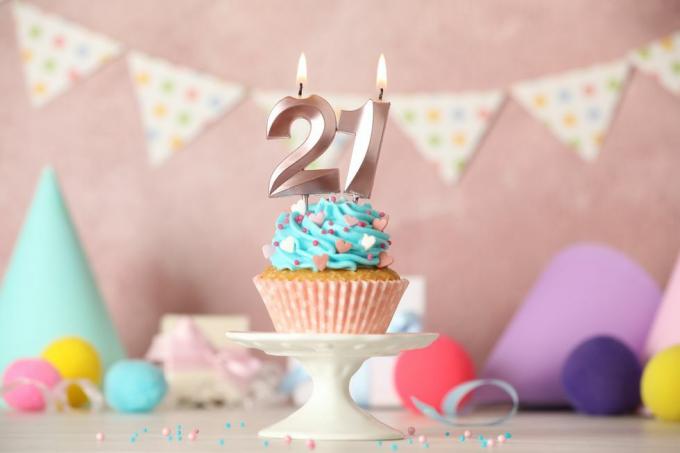 21. dzimšanas dienas kūciņa ar numuru svecēm uz balta galda