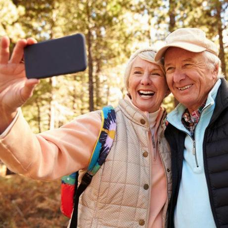 Vecākais pāris dodas pārgājienā mežā, uzņemot selfiju