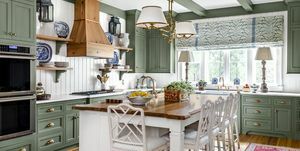virtuve ar nomierinoši zaļi krāsotiem skapjiem, spārēm un apdari, kas apvienota ar baltām paneļu sienām, griestiem un salu