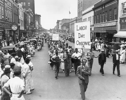 darba dienas parāde 1934. gadā, kad cilvēki staigāja pa ielu, turot zīmes, kad pūlis vēro no ietvēm