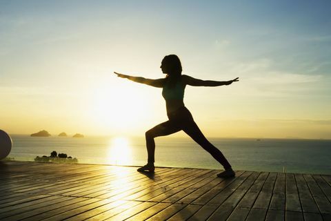 Sieviete, kas nodarbojas ar jogu pie jūras saulrieta laikā