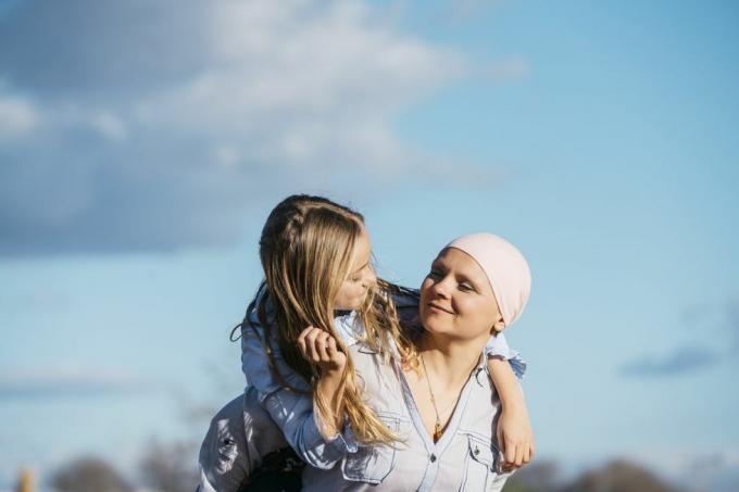 sieviete no zoda līdz vēderam, kas izstiepj rokas, lai izveidotu sirds formu, lai ierāmētu rozā lenti uz viņas baltā džempera