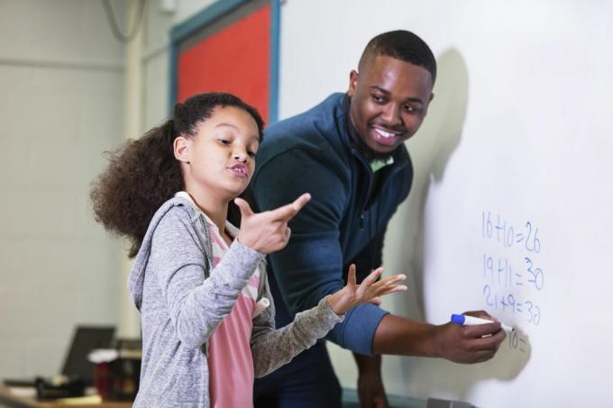 daudzrasu 9 gadus veca meitene matemātikas stundā, stāv pie tāfeles ar savu skolotāju, jaunu afroamerikāņu vīrieti 20. gados skolotājs skatās uz savu sākumskolas audzēkni un gaida, kamēr viņa mēģina izdomāt atbildi, fokuss ir uz meitene