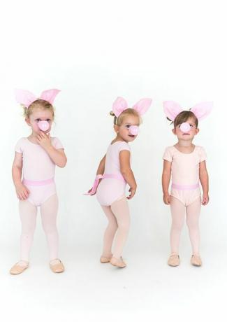mazas meitenes sārtās zeķubiksēs un onesies ar cūku ausīm un cūku purniem