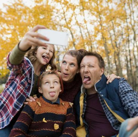 Muļķīga ģimene, kas uzņem selfijus, veido sejas rudens parkā