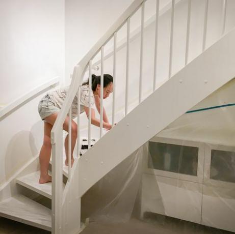sieviete, uzklājot svaigu, baltu krāsu uz kāpnēm